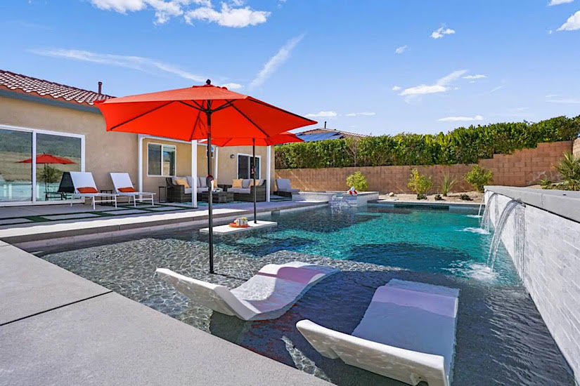 Rolling Hills: Desert Hot Springs, CA Luxury vacation home with a pool, red umbrella, lounge chairs, outdoor seating, and desert landscape in Desert Hot Springs, CA.