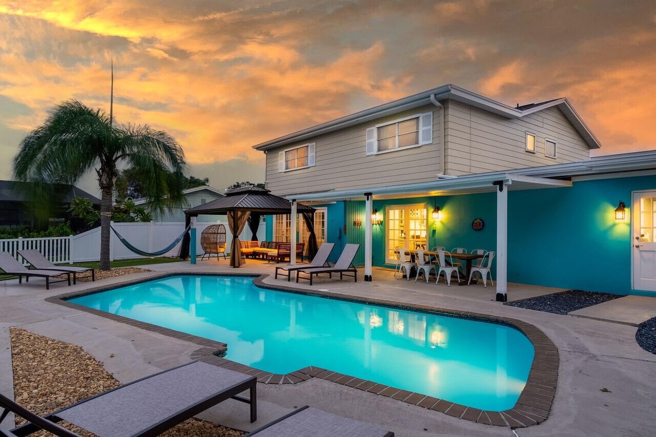 Luxury vacation home in Tampa with a swimming pool, outdoor seating, and tropical landscaping at sunset.