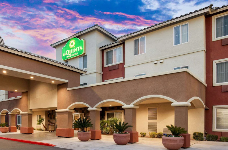 La Quinta Inn & Suites- Red Rock / Summerlin Exterior view of La Quinta Inn & Suites in Summerlin with a colorful sunset sky, featuring a green sign and welcoming entrance.