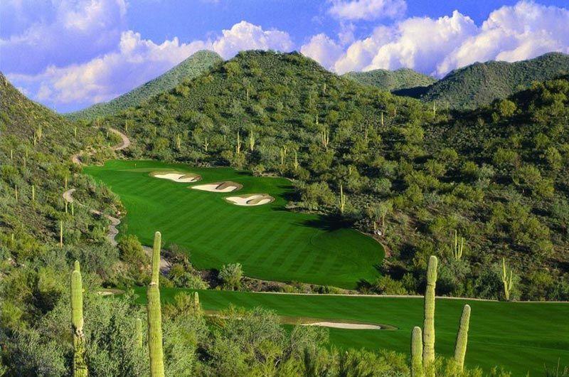 Scenic view of Quintero Golf Club in Arizona, featuring lush green fairways, desert cacti, and mountainous backdrop.
