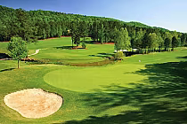 Scenic view of Limestone Springs Golf Club in Alabama with lush green fairways, trees, a sand trap, and a pond under a clear blue sky.