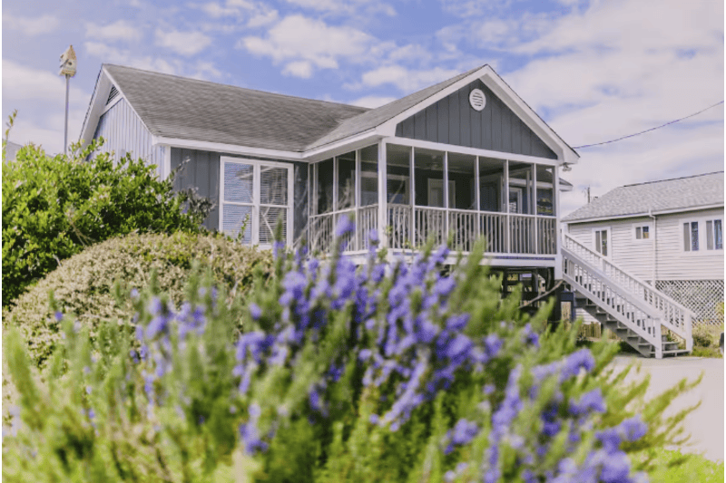 Vista Mare Vista Mare beach house with a screened porch, surrounded by purple flowers and greenery, near Garden City's seaside.