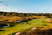 A scenic view of The Pulpit golf course in Caledon, Ontario, featuring lush green fairways, sand bunkers, and surrounding trees under a clear blue sky.