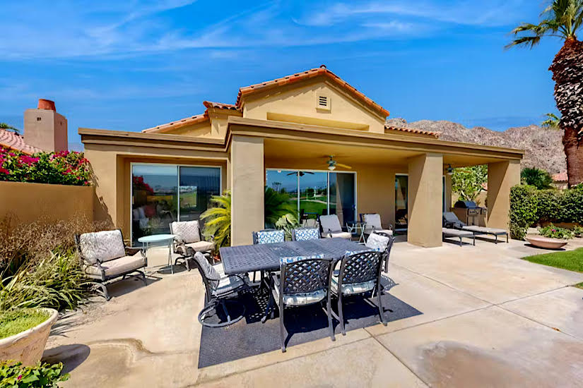 Riviera Oasis - La Quinta, CA Outdoor patio with dining table, lounge chairs, and lush landscaping at Riviera Oasis in La Quinta, CA, near golf courses.