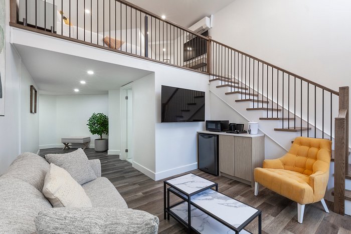 Strata Hotel - Kingston Modern hotel suite at Strata Hotel in Kingston, featuring a cozy living area with a sofa, yellow armchair, and staircase leading to an upstairs loft.