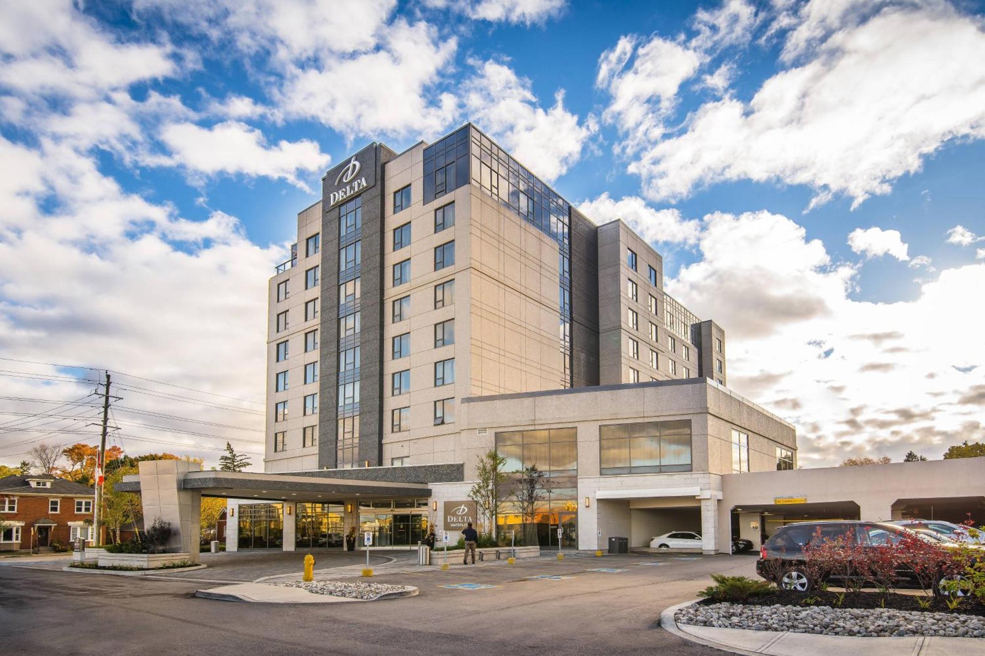 Delta Markham Modern Delta hotel building with glass windows, parking lot, and a partly cloudy sky, near leisure and corporate areas.