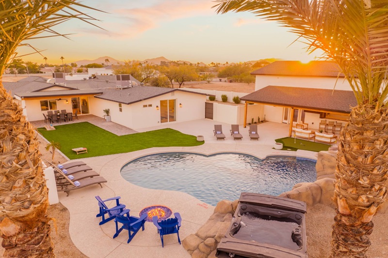 Luxurious Scottsdale vacation home with a pool, outdoor seating, and scenic desert views at sunset.