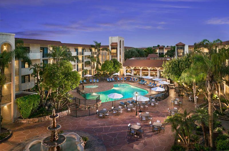 Luxurious Scottsdale hotel courtyard with a swimming pool, surrounded by palm trees, outdoor seating, and a fountain at dusk.