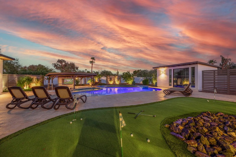 Luxurious Scottsdale vacation home with a pool, hot tub, outdoor lounge, and a mini golf course at sunset.